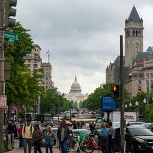 A group of people walking down a street next to tall buildings