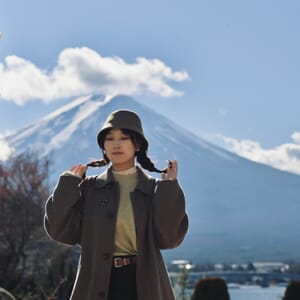 A woman standing in front of a mountain with a hat on